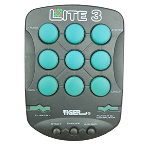 May include: A gray handheld electronic game called Lite 3 by Tiger. The game has nine blue buttons arranged in a grid pattern. The game has controls for start, on/off, and sound.