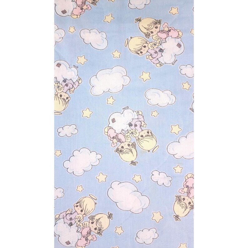 May include: Pale blue fabric featuring a repeating pattern of cartoon angel figures, white clouds, and yellow stars. The angels are in pastel colours, with blonde hair and halos. The fabric is likely for baby or children's items.