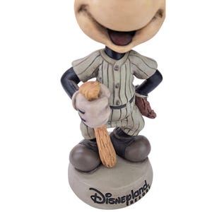 Peut inclure: Figurine Disneyland Resort de Mickey Mouse en uniforme de baseball. La figurine porte un maillot &agrave; rayures et tient une batte de baseball. La base de la figurine est grise et porte le logo Disneyland Resort.