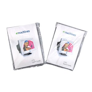 May include: Two sealed eMachines 17F3 User's Guide booklets. Each booklet features the eMachines logo and a picture of a computer monitor displaying a woman's image. The booklets are in clear plastic packaging.