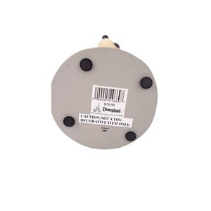 Peut inclure: Une base grise et circulaire avec quatre pieds en caoutchouc noirs. Un autocollant Disneyland est appos&eacute; sur la base, avec le texte "CAUTION: NOT A TOY - DECORATIVE ITEM ONLY." La base supporte une figurine.