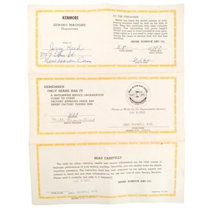 Puede incluir: Una tarjeta de garantía vintage para una máquina de coser Kenmore con el texto "Remember Only Sears Has It" y un número de teléfono para el servicio al cliente. La tarjeta está amarillenta por el paso del tiempo y tiene información escrita a mano.