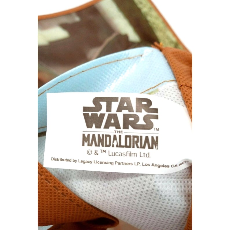 Op de afbeelding: Wit etiket met zwarte tekst die "STAR WARS -THE MANDALORIAN &copy; & TM Lucasfilm Ltd. Distributed by Legacy Licensing Partners LP, Los Angeles CA" luidt.