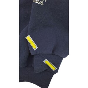 May include: Navy blue sweatshirt with yellow arrow-shaped accents on the sleeves. The cuffs are ribbed. The text "Beach, Fla." is visible on the upper left side of the sweatshirt.