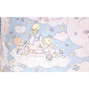 May include: A light blue fabric with a charming illustration of cherubic figures with halos, painting a pink structure amidst clouds, stars, and butterflies. A small white dog is also present. The design has a soft, pastel colour palette.