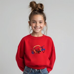 May include: A red crew neck sweatshirt with a Spider-Man design. The graphic depicts Spider-Man with a fiery ring. The sweatshirt is made of a soft material and is suitable for children.