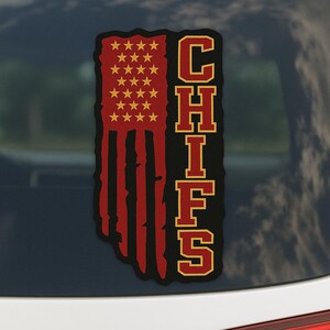May include: A Chiefs-themed sticker featuring a distressed American flag design in red, black, and gold. The word "CHIEFS" is vertically stacked in a bold, outlined font, complementing the flag's stars and stripes.