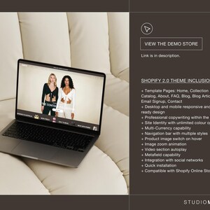 May include: A silver laptop showing a website with two models in black and white clothing. The screen displays "THE CONTO COLLECTION". The image also includes the text "VIEW THE DEMO STORE" and a list of Shopify 2.0 theme inclusions.