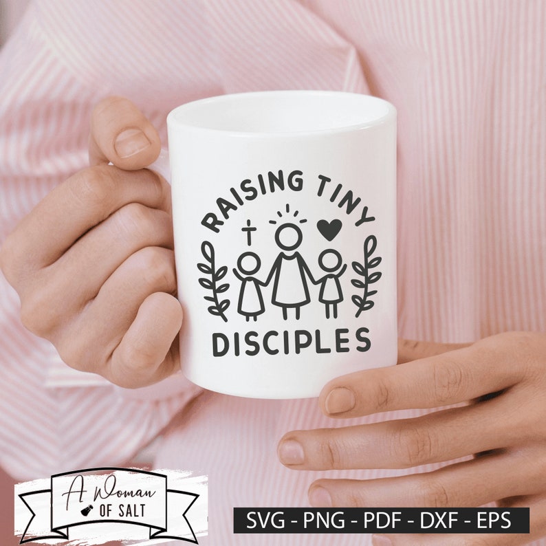 以下が含まれることがあります： 白いセラミック製のマグカップに、黒いデザインで「Raising Tiny Disciples」と書かれており、スタイリッシュなデザインで、母親と2人の子供が手をつないでいる様子が描かれています。母親は後光を放ち、頭上に十字架があります。デザインは葉の輪で囲まれています。