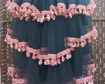 May include: Black tulle skirt with multiple layers of red and gold trim and tassels.