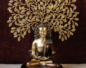 May include: A gold metal sculpture of a seated Buddha with a tree of life above his head. The sculpture is on a black base.
