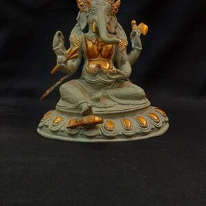 Op de afbeelding: Een groen en gouden Ganesha-beeld met een vierarmige pose, zittend op een lotusbasis met gouden accenten.