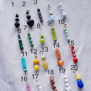 Puede incluir: Veinte cuentas de piedras preciosas surtidas en cadenas doradas, numeradas del 1 al 20. Las cuentas son de varios colores, formas y tama&ntilde;os, incluyendo turquesa, rojo, verde, amarillo, naranja, rosa y azul.