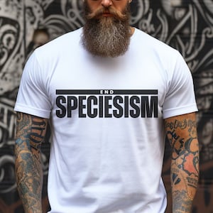 Op de afbeelding: Wit T-shirt met zwarte tekst die "END SPECIESISM" luidt in een vetgedrukt, sans-serif lettertype.