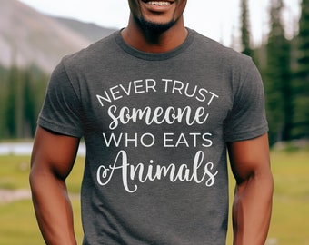 May include: A dark heather grey t-shirt with the text "NEVER TRUST someone WHO EATS Animals" printed in white.
