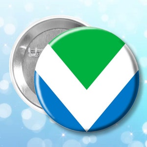 Puede incluir: Un botón verde, blanco y azul con un diseño en forma de V. El botón es circular y tiene una parte posterior plateada.