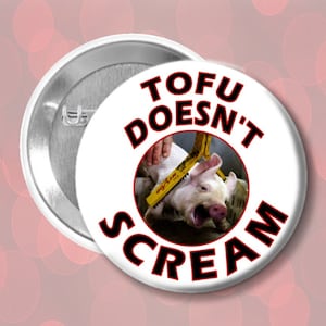 Könnte beinhalten: Ein weißer Knopf mit rotem Rand und dem Text "TOFU DOESN'T SCREAM" in Schwarz. Der Knopf zeigt eine Grafik eines geschlachteten Schweins.