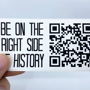 Op de afbeelding: Witte sticker met zwarte tekst die "BE ON THE RIGHT SIDE OF HISTORY" luidt en een zwart-witte QR-code.