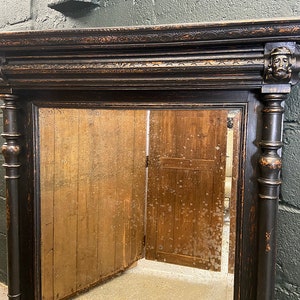 May include: A black wooden mirror with ornate carvings and a distressed finish. The mirror has a rectangular frame with a beveled edge and a simple, clear glass reflection.