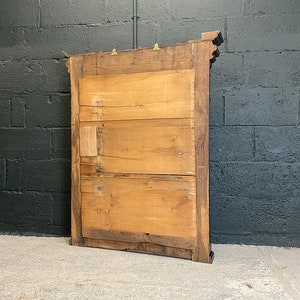 May include: A wooden framed mirror with a simple design. The mirror is rectangular and has a dark wood frame. The back of the mirror is visible, showing the wood construction.