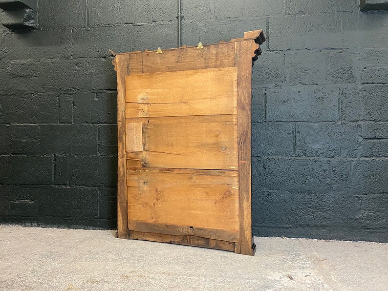 May include: A wooden framed mirror with a simple design. The mirror is rectangular and has a dark wood frame. The back of the mirror is visible, showing the wood construction.
