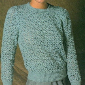 May include: A light blue knitted sweater with a delicate openwork pattern. The sweater has a round neckline and long sleeves.
