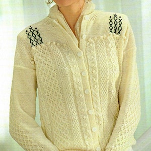May include: A white knitted cardigan with a button-up front and a cable knit pattern. The cardigan has black embroidered details on the shoulders.