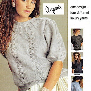 Può includere: Una donna indossa un maglione grigio chiaro con un delicato motivo a pizzo. Il maglione è realizzato in angora, alpaca, cashmere e lana merino. Il testo "Angora" è scritto in corsivo nell'angolo in alto a destra dell'immagine. Il testo "one design - four different luxury yarns" è scritto in nero sul lato destro dell'immagine.