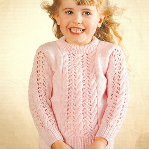 May include: A pink knitted sweater with a cable knit pattern and lace detailing. The sweater has a round neckline and long sleeves. The sweater is easy to knit.