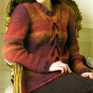 May include: A knitted sweater with a tie-front detail. The sweater is made in a gradient of orange, red, and purple yarn.