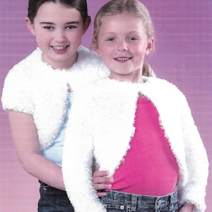 May include: Two young girls wearing white, fluffy bolero jackets. The jackets have a soft, textured appearance and are paired with jeans and a pink top. The background is a gradient of purple.