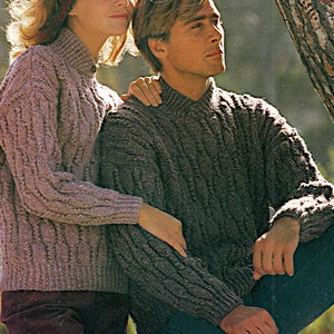 May include: Two cable knit sweaters in a light purple and a dark brown color. The sweaters have a high neck and a relaxed fit.