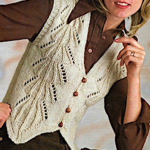 May include: A white crocheted vest with a V-neck and button closure. The vest has a delicate lace pattern and is worn over a brown shirt.