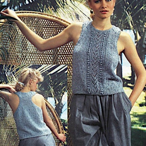 May include: A light blue sleeveless knitted top with a lace pattern. The top is worn by a person with a light blue skirt and is photographed against a backdrop of tropical plants.