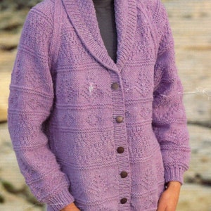 May include: A purple knitted cardigan with a wide collar and button closure. The cardigan has a textured pattern and is shown being worn by a person.