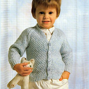 May include: A light blue knitted cardigan with a button fastening. The cardigan is worked in a moss stitch and features a white toy tiger.