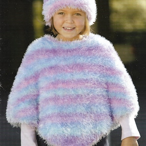 Op de afbeelding: Een meisje draagt een blauwe en paarse gestreepte, fuzzy poncho met een bijpassende fuzzy muts.