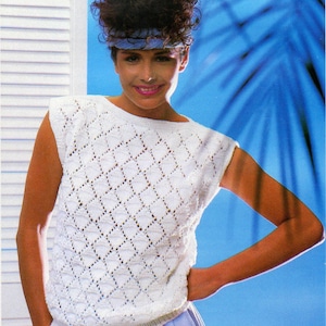 以下が含まれることがあります： ダイヤモンド柄の白いノースリーブニットトップ。トップは丸首で、軽量の糸で作られています。