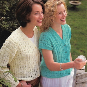 Könnte beinhalten: Zwei Frauen tragen gehäkelte Strickjacken. Die Frau links trägt eine cremefarbene Strickjacke mit Knöpfen. Die Frau rechts trägt eine türkisfarbene Strickjacke mit Knöpfen.