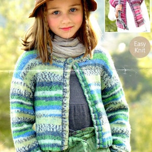 Könnte beinhalten: Ein junges Mädchen trägt einen grün-blau-weiß gestreiften Cardigan mit einem braunen Hut. Der Cardigan hat einen Knopfverschluss und ist mit einem strukturierten Muster gestrickt. Das Mädchen trägt auch einen grünen Rock und einen Schal.