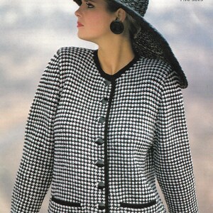 May include: A black and white houndstooth knit cardigan with black buttons and a black trim. The cardigan has a pocket on the left side. The model is wearing a black skirt and a wide-brimmed black hat.
