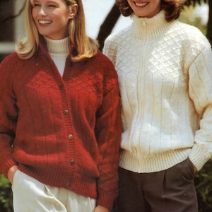 May include: Two women wearing knitted sweaters. The woman on the left is wearing a red sweater with a button-up front and a white turtleneck underneath. The woman on the right is wearing a white sweater with a high neck and a diamond pattern.