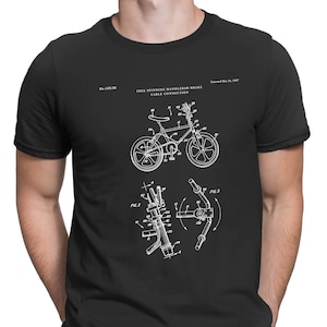 May include: Black t-shirt with a white graphic of a bicycle patent drawing. The patent number is 4,403,011 and the patent date is March 21, 1983. The text "FREE SPINNING HANDLEBAR BRAKE CABLE CONNECTION" is also included in the graphic.