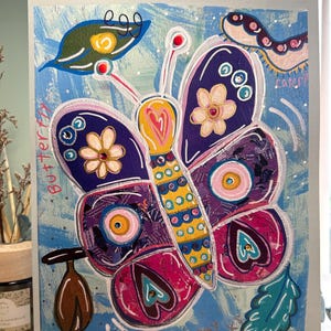 May include: Vibrant butterfly artwork with the words "butterfly" and "chrysalis" on a light blue backdrop. The butterfly features purple, pink, yellow, and blue details. The artwork includes a caterpillar and leaves.