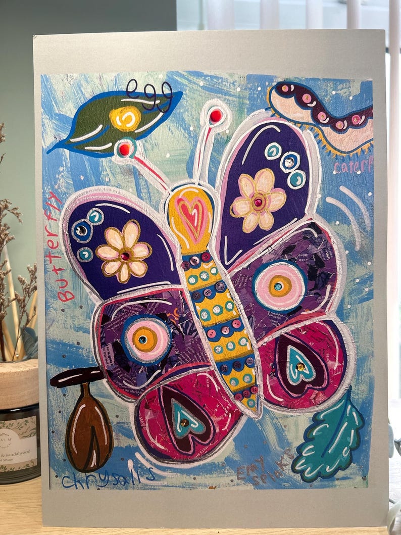 May include: Vibrant butterfly artwork with the words "butterfly" and "chrysalis" on a light blue backdrop. The butterfly features purple, pink, yellow, and blue details. The artwork includes a caterpillar and leaves.