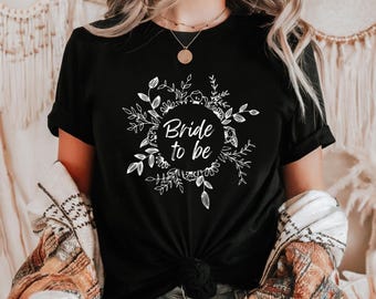 Puede incluir: Camiseta negra con un diseño floral blanco y el texto "Bride to be" en un círculo.