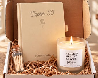 May include: A gift box containing a beige journal with the text Capter 50 and Maria Garcia, a small glass bottle filled with matches, and a lit candle in a frosted glass jar with a label reading In Loving Memory of Your Forties, 369 grams.