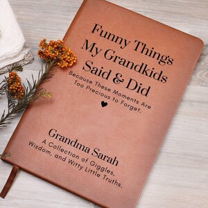 May include: A brown leather journal with the title "Funny Things My Grandkids Said & Did" and the text "Because These Moments Are Too Precious to Forget." The journal is personalized with the name "Grandma Sarah" and the text "A Collection of Giggles, Wisdom, and Witty Little Truths."