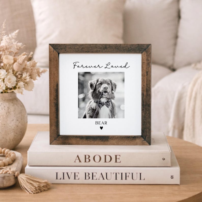 Puede incluir: Un marco de fotos cuadrado de madera con una imagen en blanco y negro de un perro con pajarita. El texto "Forever Loved" est&aacute; encima de la foto, con el nombre "BEAR" y un coraz&oacute;n debajo. El marco est&aacute; sobre dos libros.