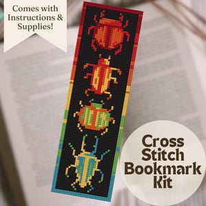 May include: A cross stitch bookmark kit featuring a black background with colorful beetle designs. The bookmark has a gradient of colors, including red, orange, yellow, green, and blue. The text "Cross Stitch Bookmark Kit" is on a white circle.